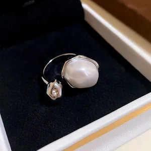Close-up of a silver open ring with a large baroque pearl in a black velvet jewelry box