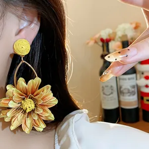 Close-up of yellow raffia flower earrings with a warm vacation-style aesthetic.