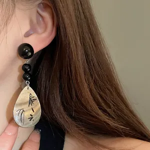 Nahaufnahme von Vintage-Ohrringen im chinesischen Stil mit Bambusgravur an einem Modell