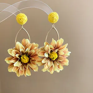 Detailed macro view of yellow fabric dahlia earrings with woven raffia studs for resort style