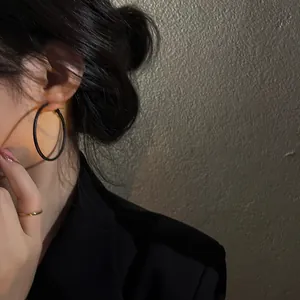 Close-up detail of a minimalist black geometric hoop earring worn by a model