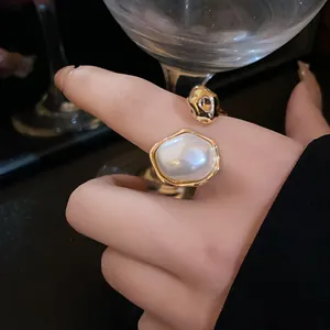 Detail of a vintage gold-plated open ring with an irregular pearl on an index finger