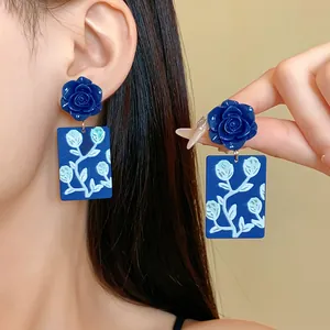 Detailaufnahme der blauen Harz-Rosenohrringe mit floral bedruckten rechteckigen Anhängern