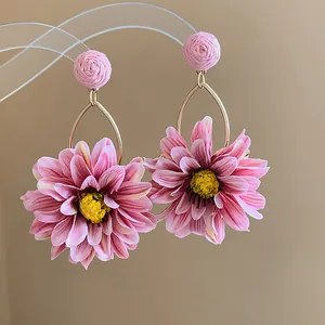 Detailed close-up of pink raffia and fabric flower drop earrings with gold-tone hoops