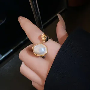 Detail showing irregular oval pearl gold open ring with retro luxury design aesthetic.