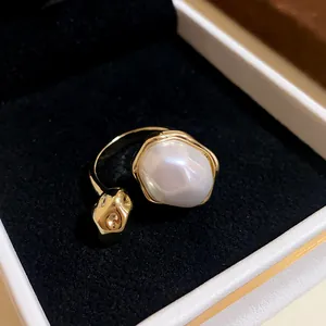 Close-up detail of a baroque pearl and gold textured element on an adjustable open ring.