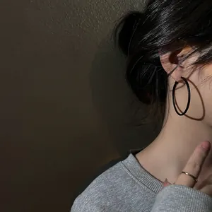 Large black matte metal hoop earrings worn by a model in a minimalist chic style