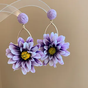 Close-up of purple fabric floral earrings with raffia wrapped studs for vacation style.