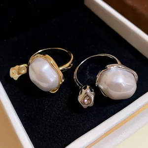 Macro detail of gold and silver plated adjustable rings featuring large irregular pearls