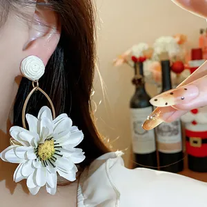 Close-up of elegant holiday style fabric raffia flower earring worn by a model