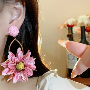 Detailed view of oversized pink fabric raffia flower earrings in a vibrant vacation style
