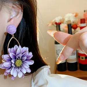 Close-up of elegant purple fabric flower earrings worn on the ear for a vacation look