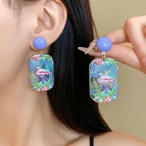 Nahaufnahme der Acryl-Ohrringe mit tropischem Flamingo-Print und leuchtend lila Steckern.