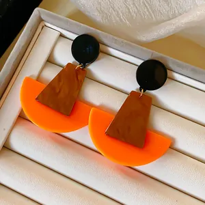 Detailaufnahme geometrischer Acryl-Ohrhänger mit lebhaftem Orange und braunem Marmormuster