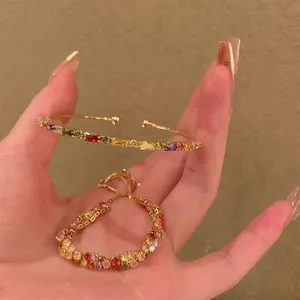 Dettaglio di bracciali dorati con vivaci pietre di zirconia cubica multicolore.
