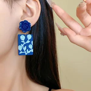 Nahaufnahme modischer blauer Acryl-Rosenohrringe mit weißen tropischen Blumenmustern