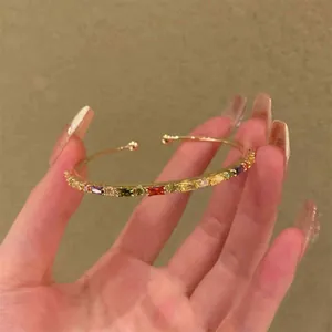 Vista dettagliata di un bracciale rigido dorato con vivaci zirconi baguette multicolore