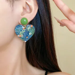 Detailansicht eines herzförmigen tropischen Blumen-Acrylohrrings am Ohr getragen
