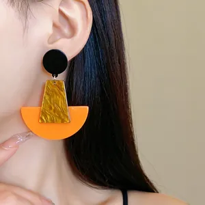 Detailaufnahme großer geometrischer Acryl-Ohrringe in Orange und Schildpatt-Optik.