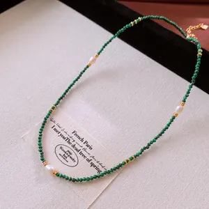 Vista dettagliata di una collana di malachite verde con perle bianche e dettagli in oro