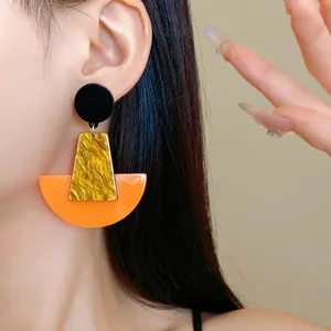 Detailansicht markanter geometrischer Acryl-Ohrringe mit kräftigem Orange und Marmor.
