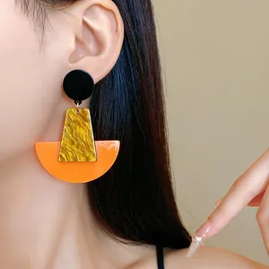 Detailansicht eines Models mit kräftigen geometrischen Acryl-Ohrhängern in bunten Farben