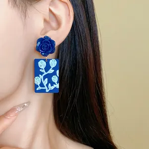 Nahaufnahme von blauen Rosen-Acryl-Ohrringen mit tropischen Blumenmustern an einem Model