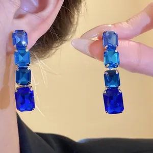 Gros plan de boucles d'oreilles en cristal bleu carré au design rétro élégant