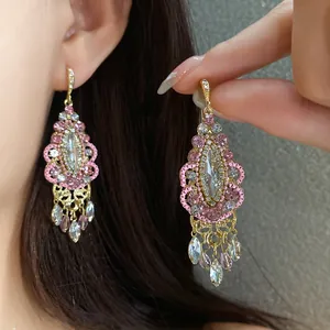 Close-up detail of vintage ethnic tassel earrings with pink rhinestones and gold plating