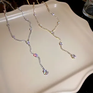 Elegant silver and gold zircon teardrop tassel necklace displayed on a beige tray