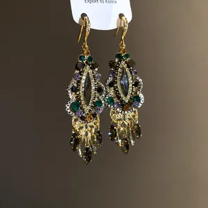 Close-up of vintage ethnic drop earrings with colorful rhinestones and gold-tone fringe