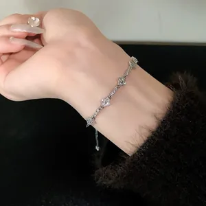 Close-up view of a silver adjustable bracelet with sparkling zircon clover charms on wrist.