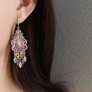 Close-up view of a vintage ethnic style pink rhinestone tassel earring being worn on an ear.