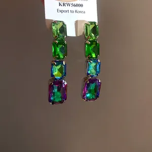 Gros plan de boucles d'oreilles pendantes carrées en cristal multicolore style vintage.