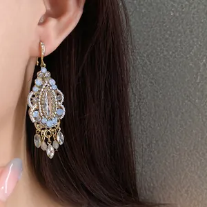 Detailed close-up of elegant ethnic rhinestone water drop tassel earrings worn on model's ear