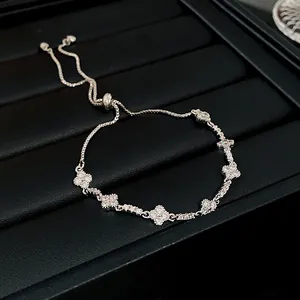 Macro detail view of a silver-toned adjustable bracelet featuring zircon flower charms