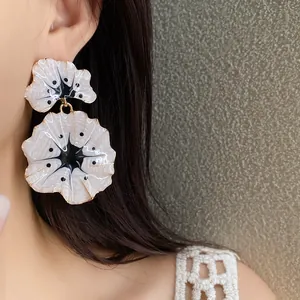 Detailed macro shot of elegant white oil-dripped floral drop earrings worn by a model