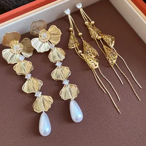 Detailed macro view of vintage gold-plated floral pearl and conical drop earrings.