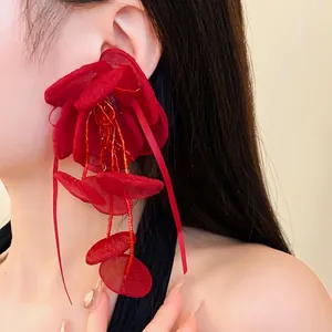 Eleganti orecchini a fiore in rete rossa con lunghe nappine di perline su una modella