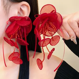 Dettaglio ravvicinato di orecchini a fiore in rete rossa con nappe di perline chic.