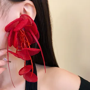 Orecchini a fiore in rete rossa con eleganti nappe di perline su orecchio di una modella