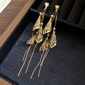 Close-up of golden 18K gold-plated tassel earrings with filigree detail