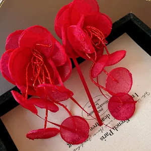 Vista dettagliata degli orecchini a fiore in rete rossa con nappe di perline e petali