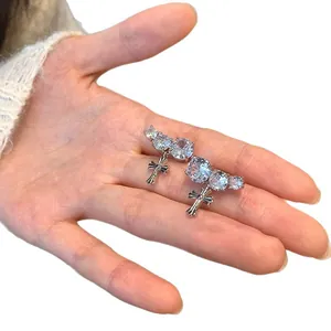 Silver-tone cross ear cuffs with round sparkling cubic zirconia displayed on a palm