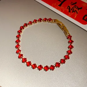 Detail view of gold-plated bracelet featuring square-cut red cubic zirconia stones