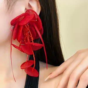 Vista dettagliata di orecchini a fiore in rete rossa con nappe di perline su modella