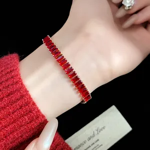 Close-up of a vintage gold bracelet with rectangular red zircon stones worn on an elegant wrist