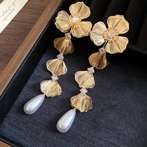 Macro view of gold floral earrings with zircon stones and pearl drops in a gift box