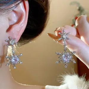 Detailed view of sparkling zirconia snowflake earrings with silver posts for winter