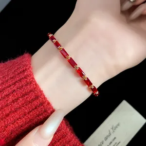 Close-up of elegant red zircon rectangular bracelet on wrist with red sweater.